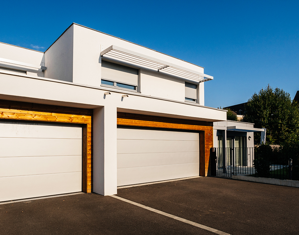Modern house architecture style with large garage automated door entrance - clear blue sky